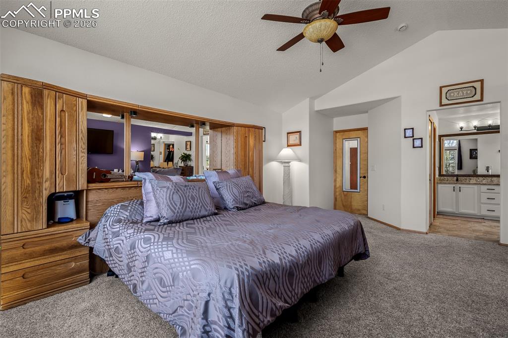 Image 31 of 50: Primary bedroom with aulted ceiling with a ceiling fan.