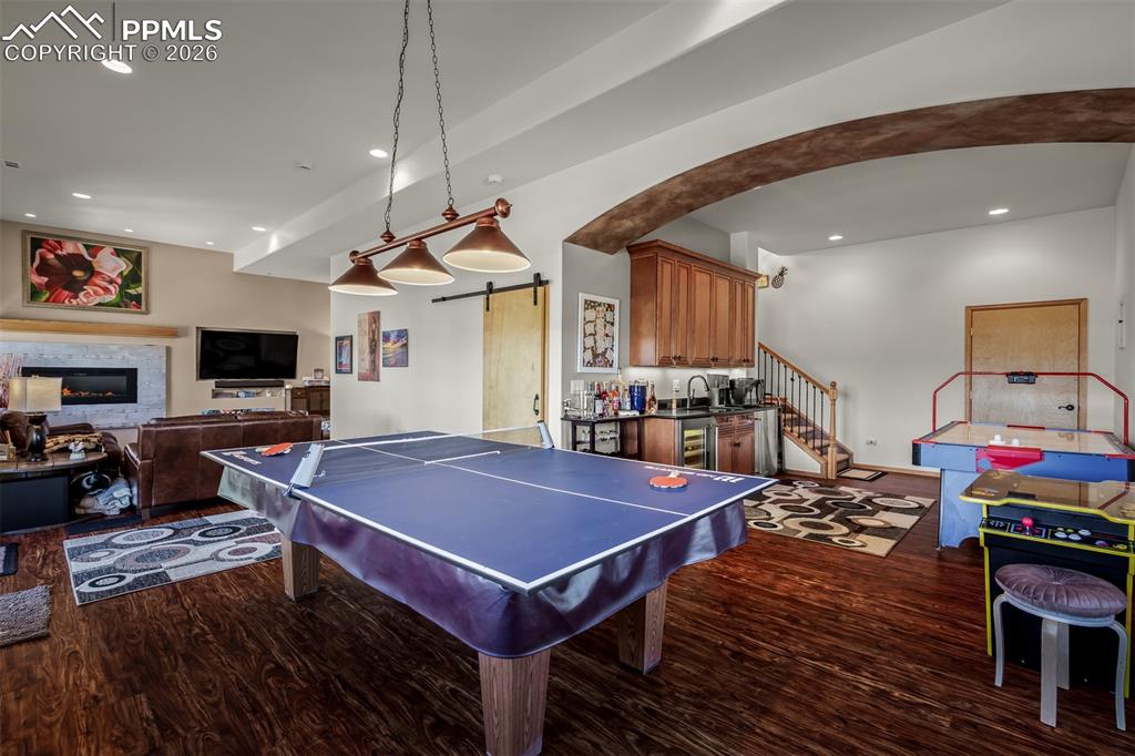 Image 36 of 50: Spacious recreational area featuring wood-finish flooring, a built-in wet b