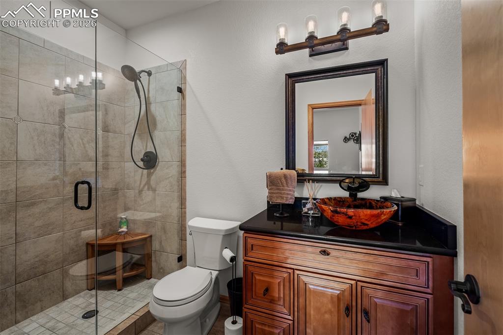 Image 38 of 50: Walk-in shower with clear glass enclosure custom tile and bowl sink serving