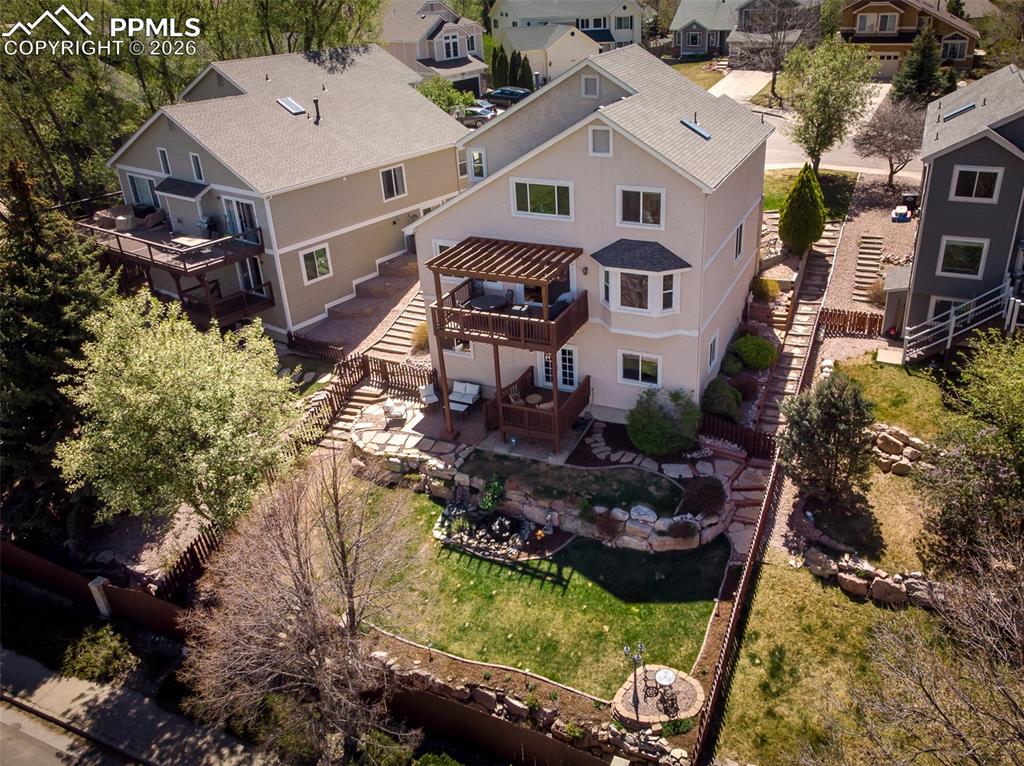 Image 47 of 50: View of back yard with terraced landscaping and mature trees