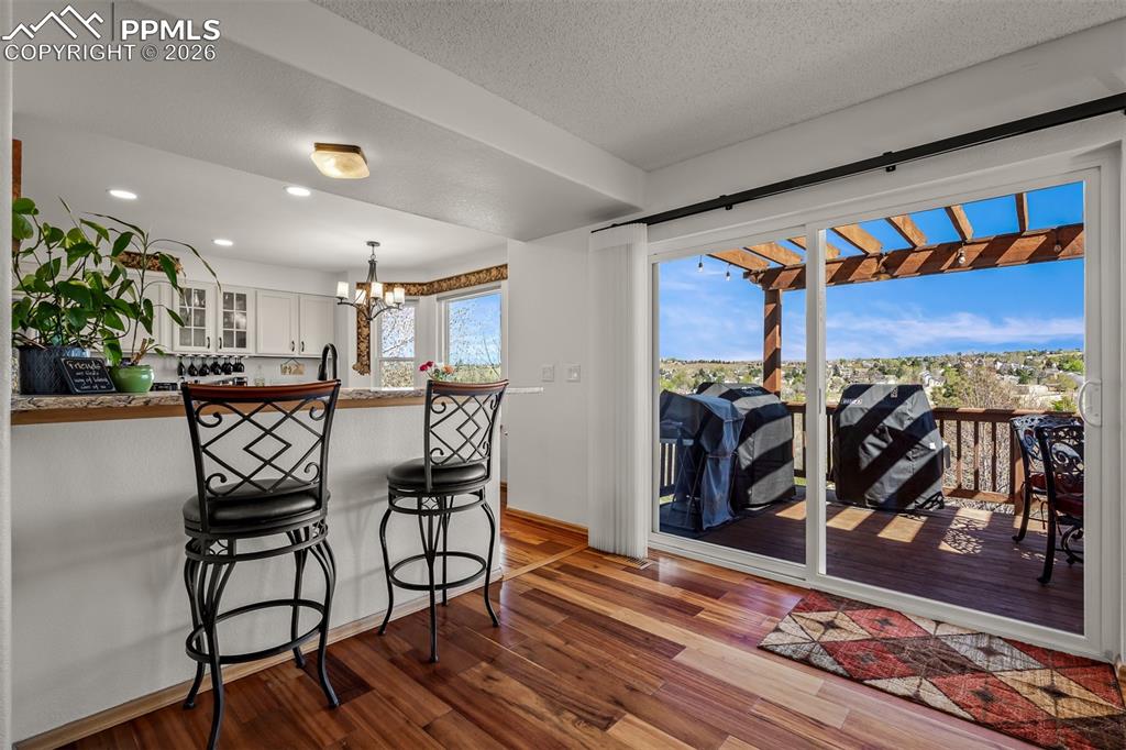 Image 8 of 50: Wide sliding glass doors open to the upper outdoor deck with a pergola and 