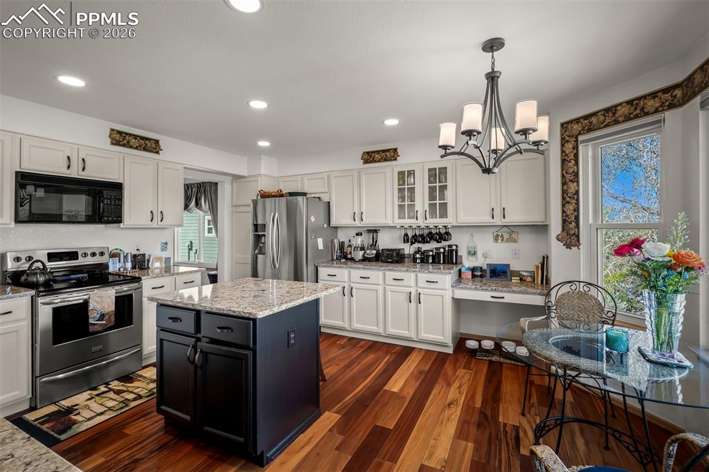 Image 9 of 50: Kitchen featuring Brazilian Koa hardwood flooring, white cabinetry, granite