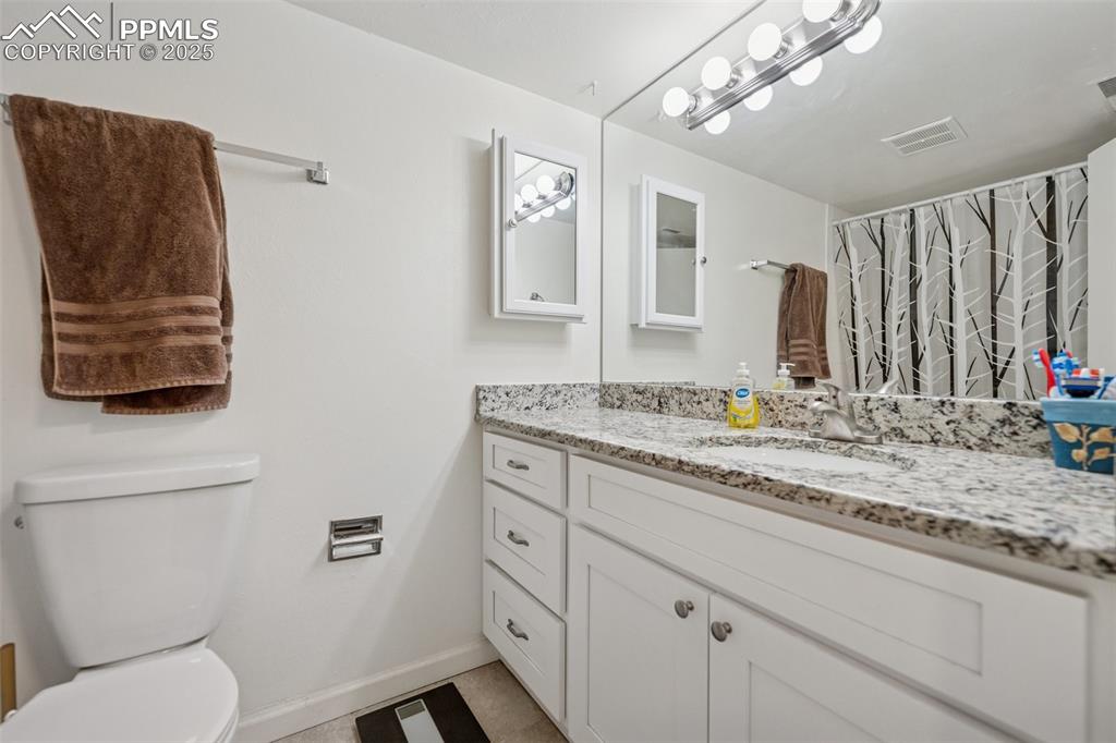 Image 9 of 11: Updated bathroom with granite vanity, modern fixtures, and tile flooring.