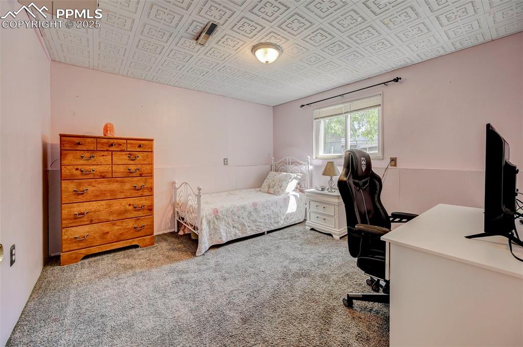 Image 18 of 30: Bedroom with a desk and carpet floors