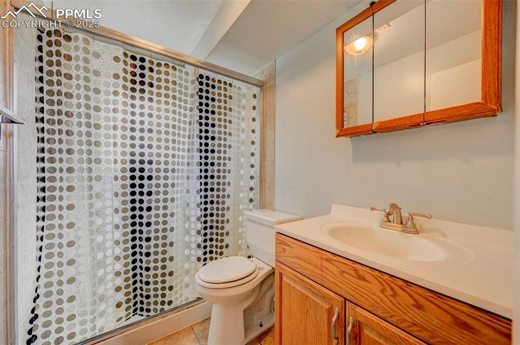 Image 19 of 30: Bathroom with a shower, vanity, and tile patterned flooring