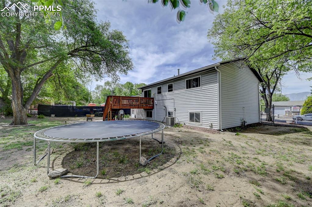 Image 27 of 30: Rear view of property with a trampoline, a deck, and stairs