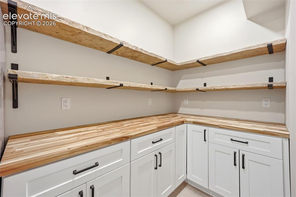 Image 13 of 50: Hidden pantry complete with butcher block counter and rough edge wooden she