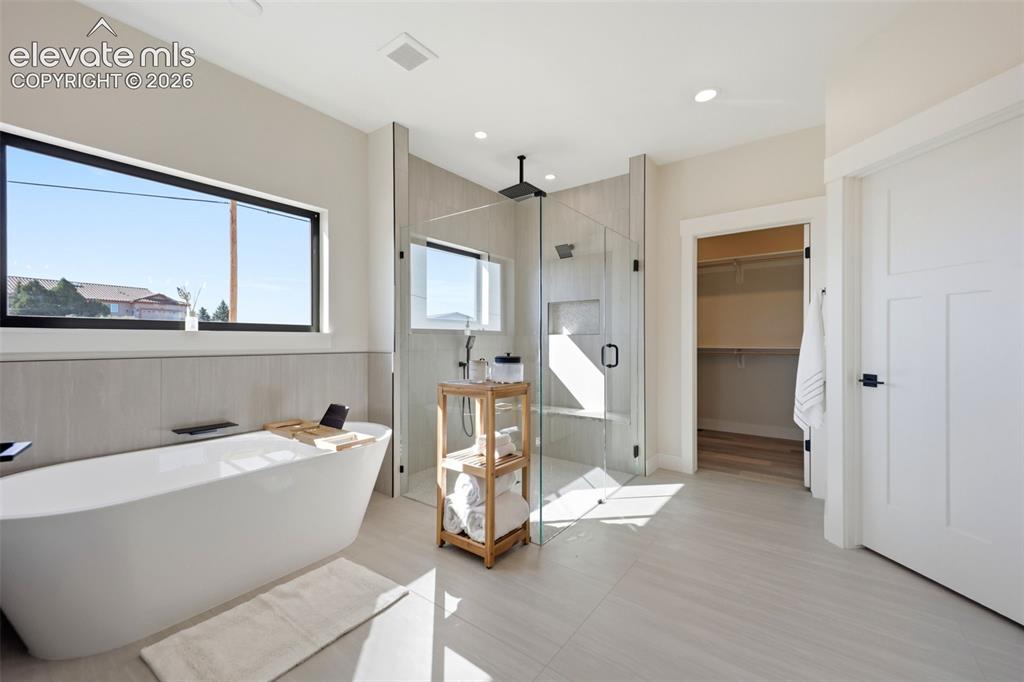 Image 22 of 50: Primary bath with free standing soaking tub, glass walk in shower, walk in 