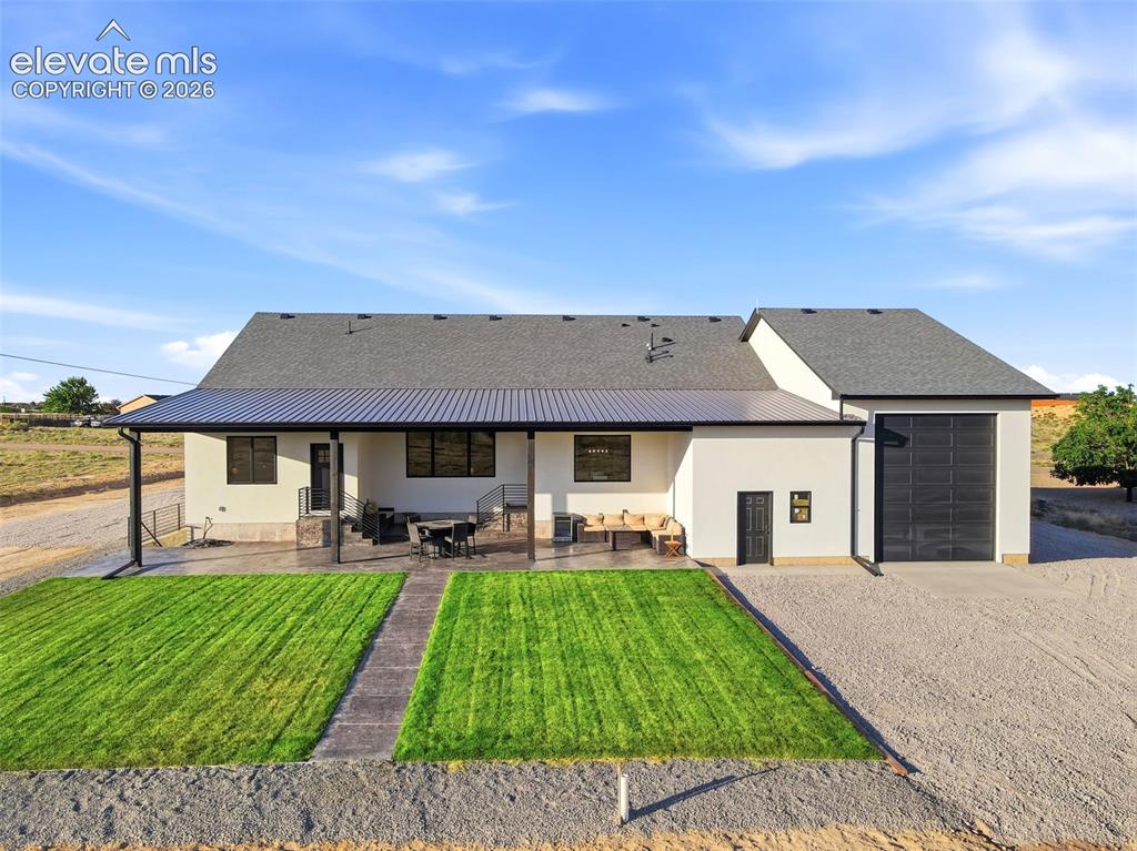 Image 50 of 50: Back of the home with exit door of pass thru RV garage, Landscaped yard, an