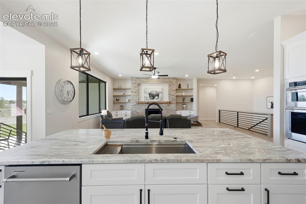 Image 9 of 50: Kitchen island with lighting, sink and dishwasher