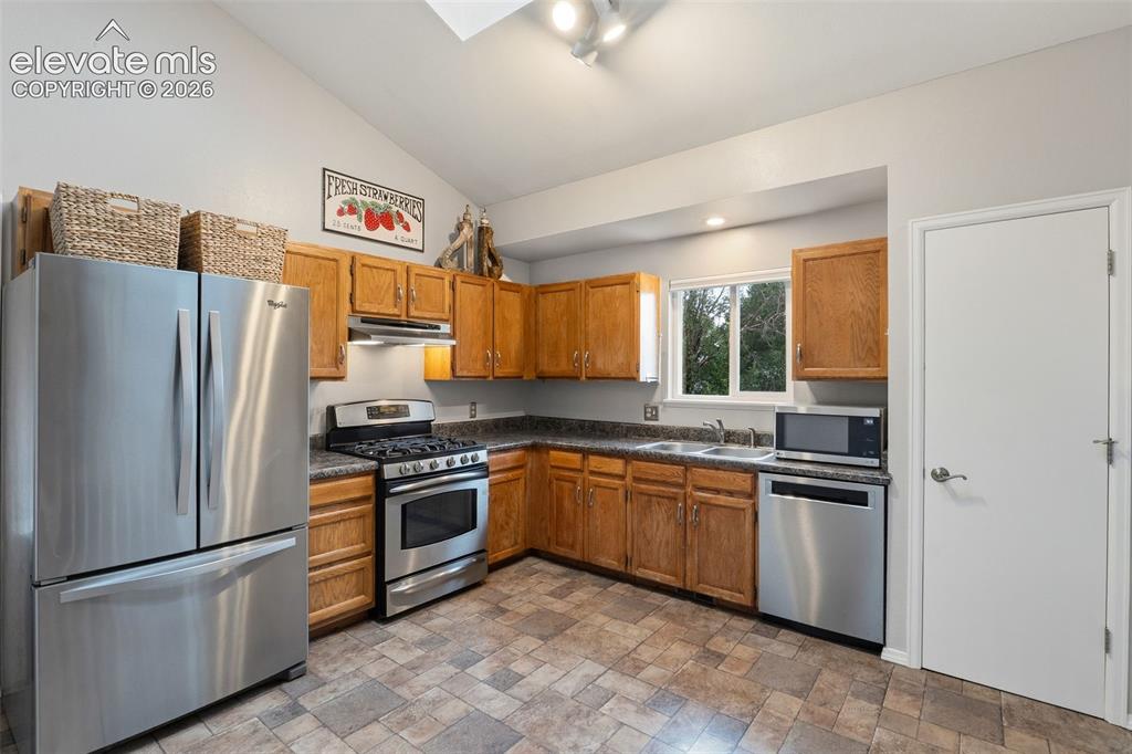 Image 10 of 37: Kitchen featuring wood cabinetry, stainless steel appliances, a double basi