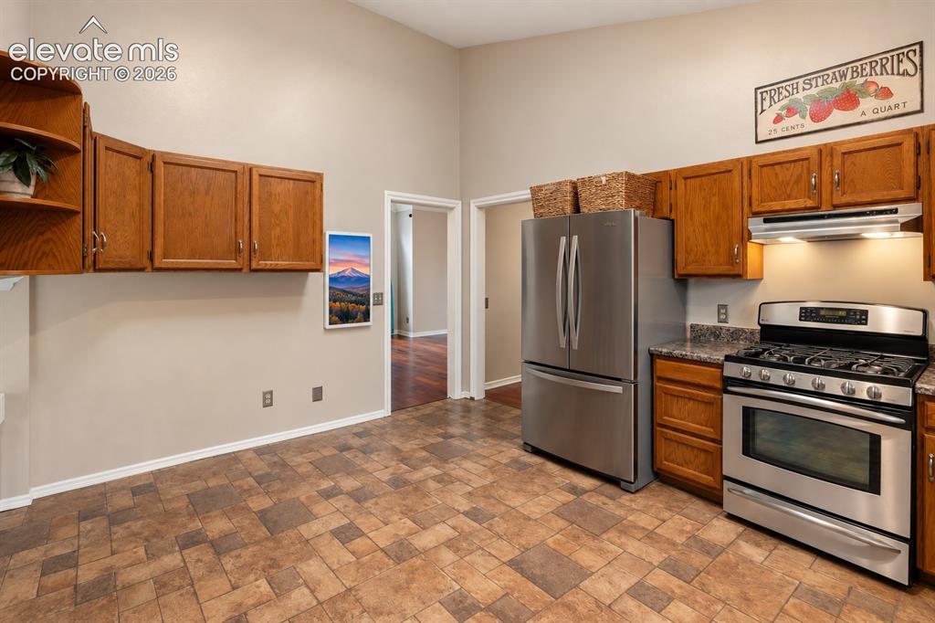 Image 12 of 37: Kitchen featuring warm wood cabinetry, stainless steel appliances, patterne