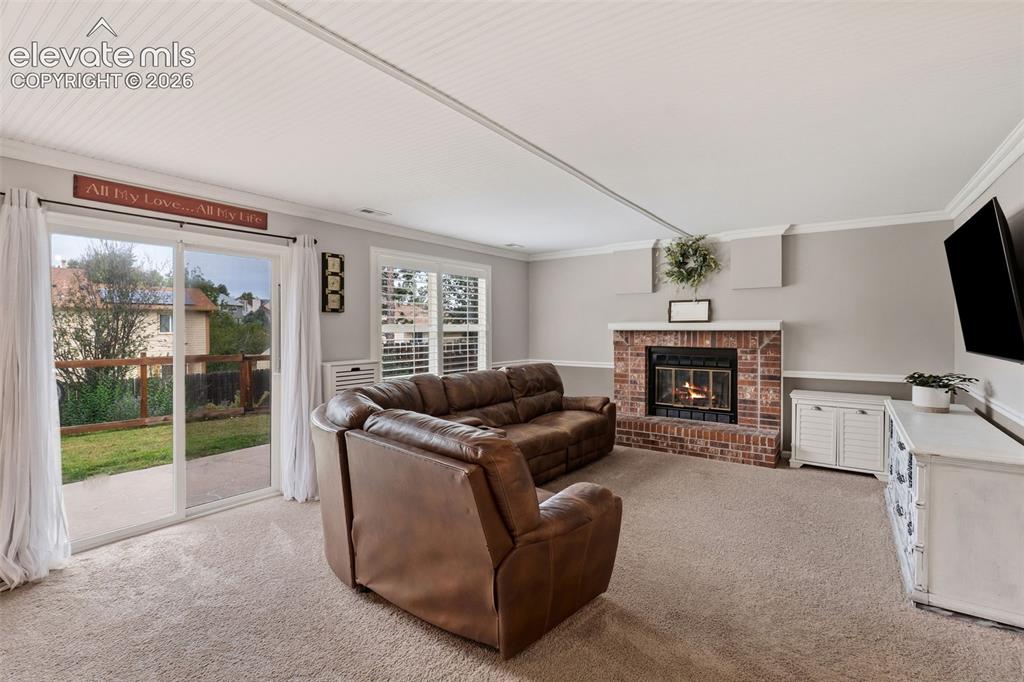 Image 13 of 37: Spacious family room featuring a brick fireplace with mantel, wall-mounted