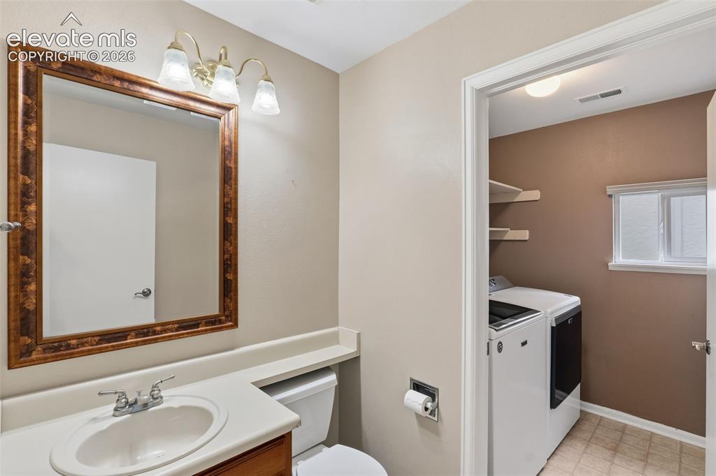 Image 15 of 37: Bathroom vanity with a white countertop and a framed mirror