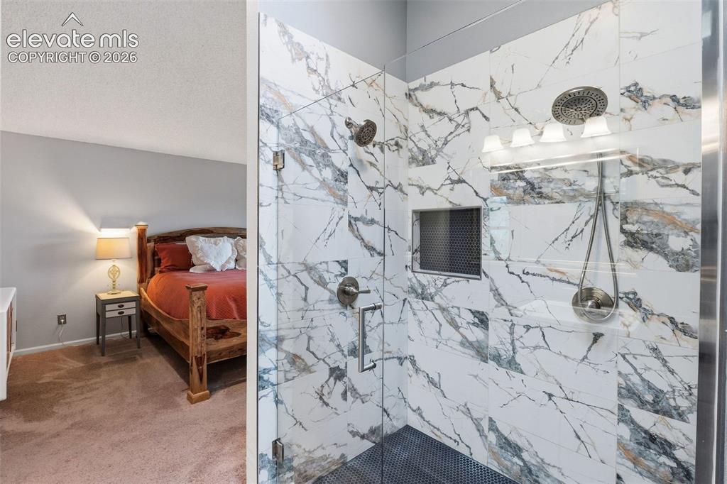 Image 19 of 37: Walk-in shower with full-height marble-patterned tile, glass enclosure, rec
