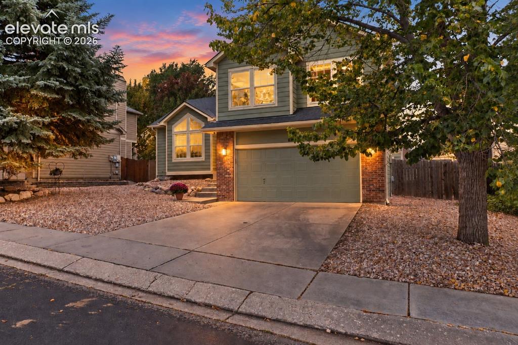 Image 2 of 37: Two-story residence with siding and stone accents, concrete driveway, and a