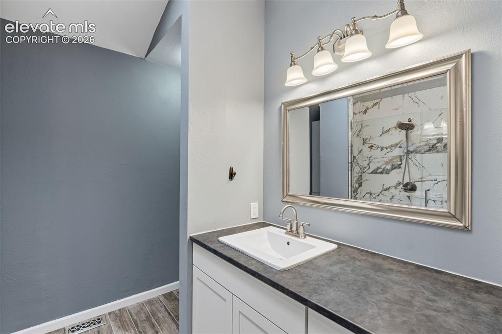 Image 20 of 37: Single vanity with a white rectangular sink, brushed nickel faucet, dark co