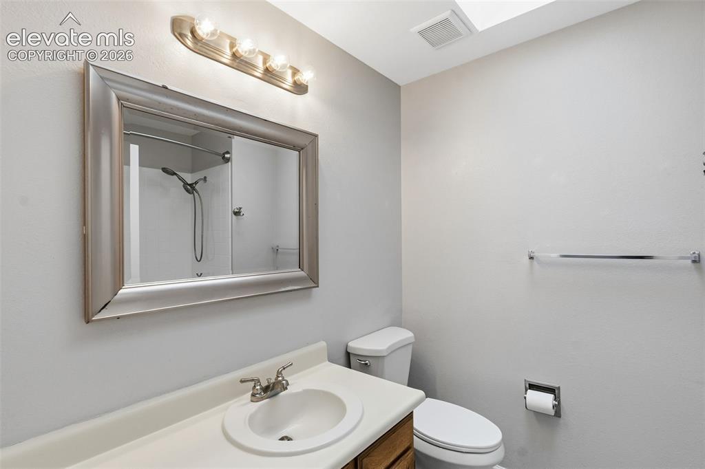 Image 24 of 37: Vanity with integrated sink and chrome faucet, framed mirror with vanity li