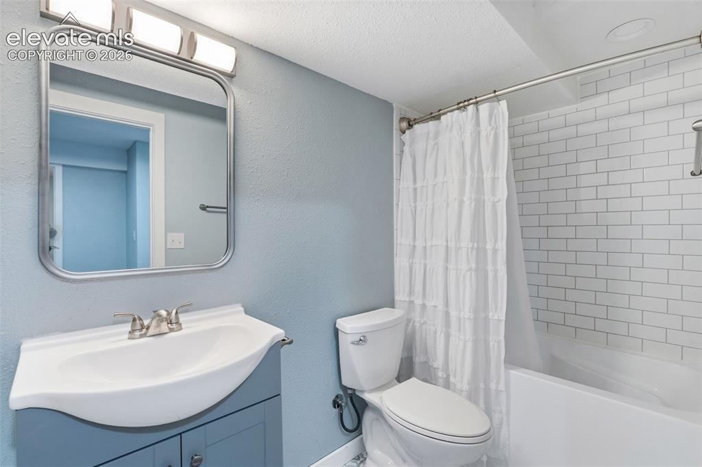 Image 26 of 37: Bathroom featuring a blue vanity with an integrated sink, brushed nickel fa