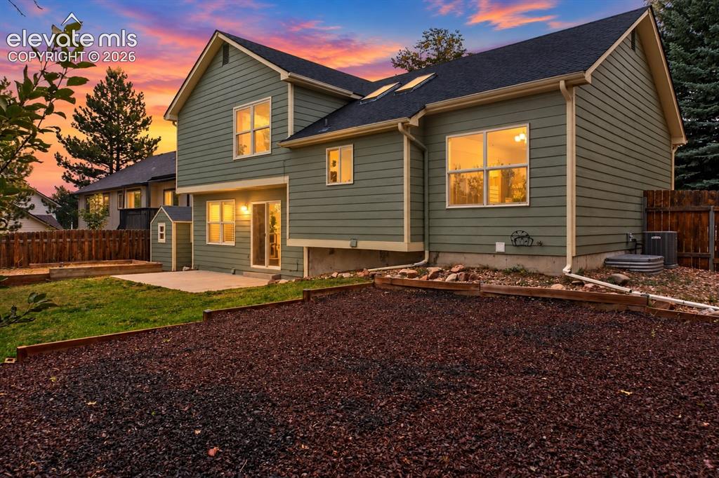 Image 28 of 37: Green siding exterior with a dark shingle roof, featuring multiple windows