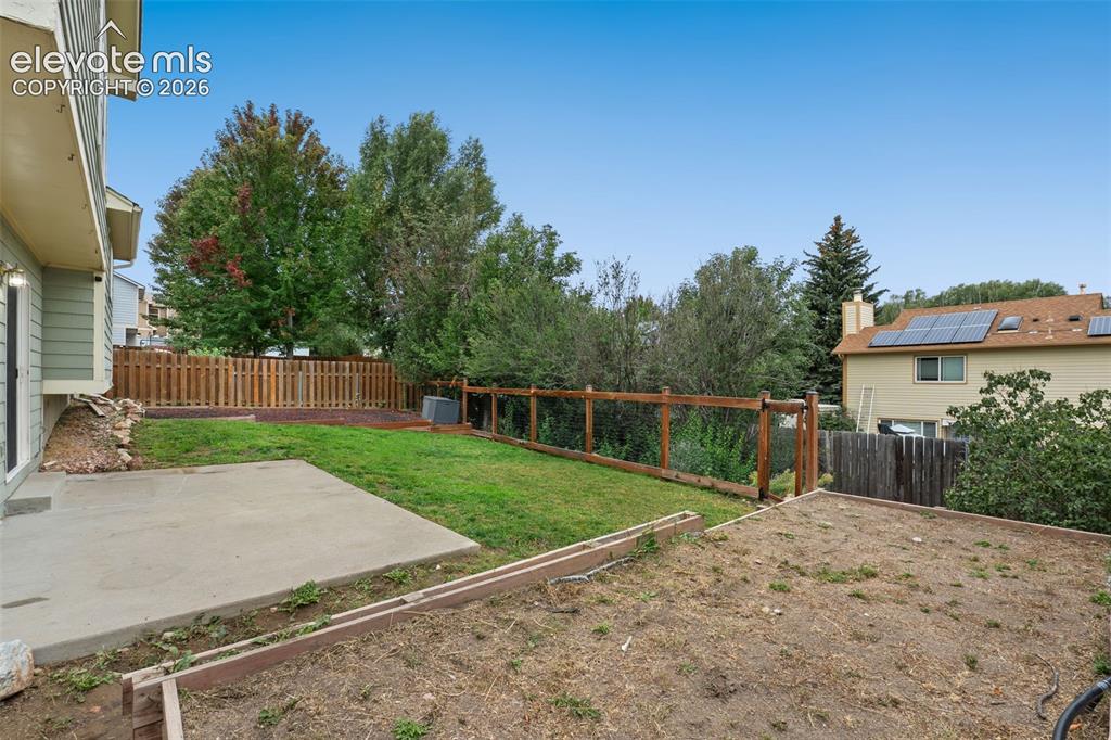 Image 29 of 37: Expansive backyard featuring a concrete patio, wood fencing, and a terraced