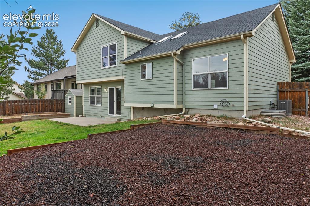 Image 30 of 37: Horizontal siding exterior with multiple windows, concrete patio, and a she