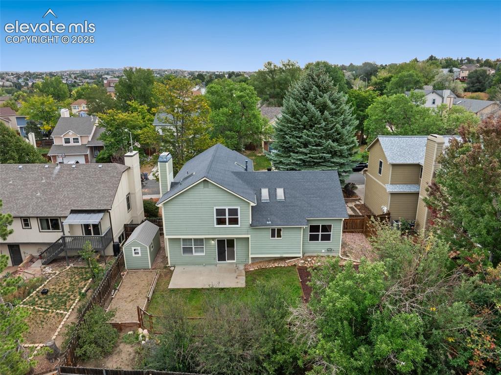 Image 32 of 37: Rear exterior featuring green siding, a shingled roof, a ground-level patio