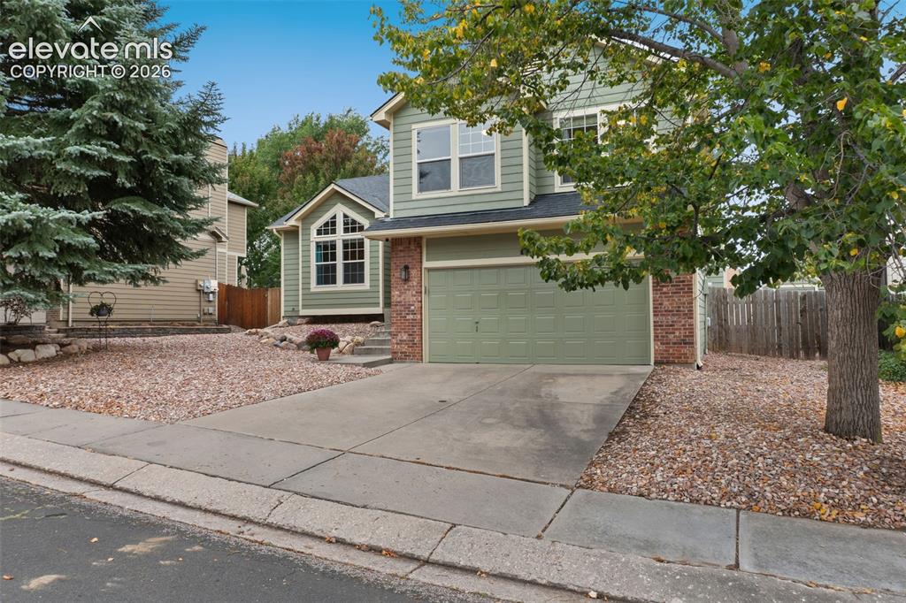 Image 5 of 37: Two-story exterior with a brick and siding facade, an attached garage, and 