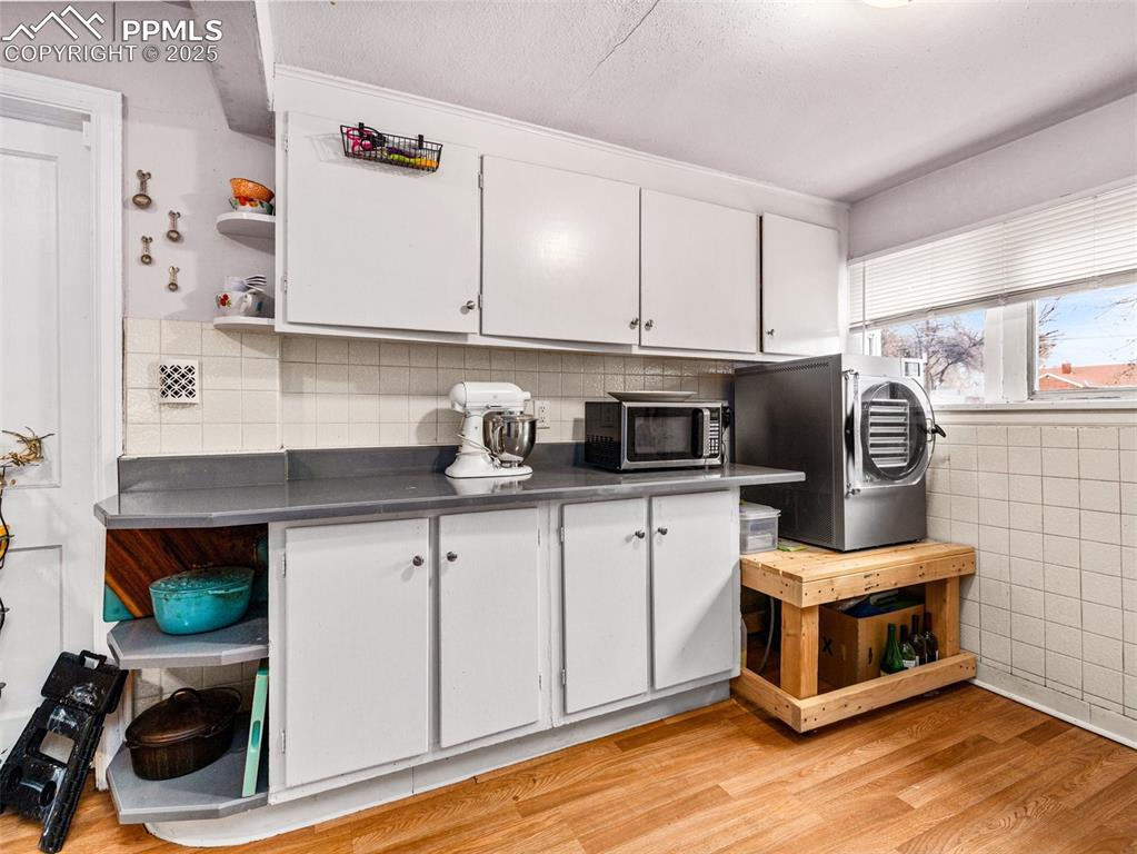 Image 13 of 33: Kitchen featuring open shelves, white cabinetry, washer / dryer, light wood