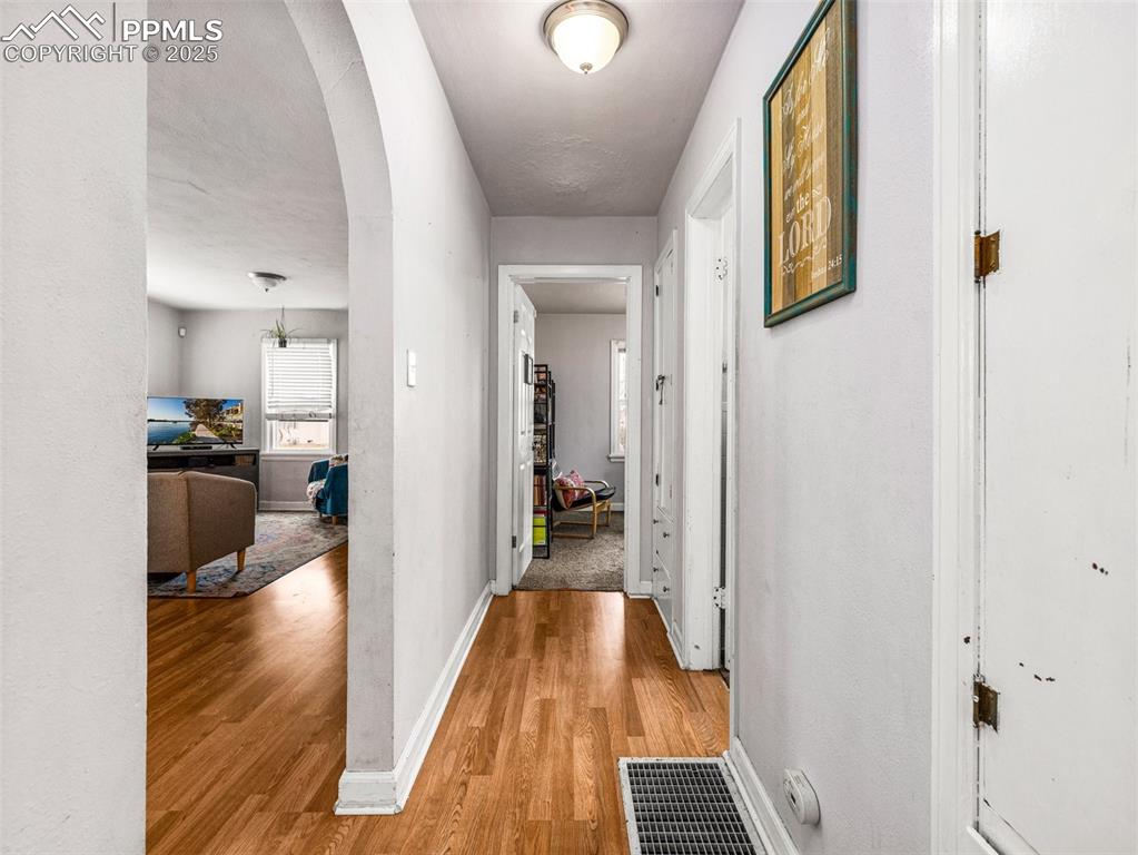 Image 16 of 33: Hall featuring arched walkways and light wood-type flooring