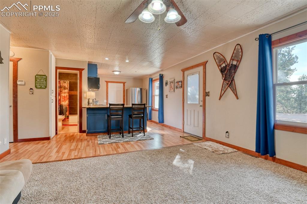 Image 19 of 43: Kitchen featuring blue cabinets, light carpet, a kitchen bar, a peninsula,
