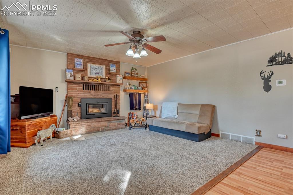 Image 21 of 43: Living area featuring a fireplace, a ceiling fan, and wood finished floors