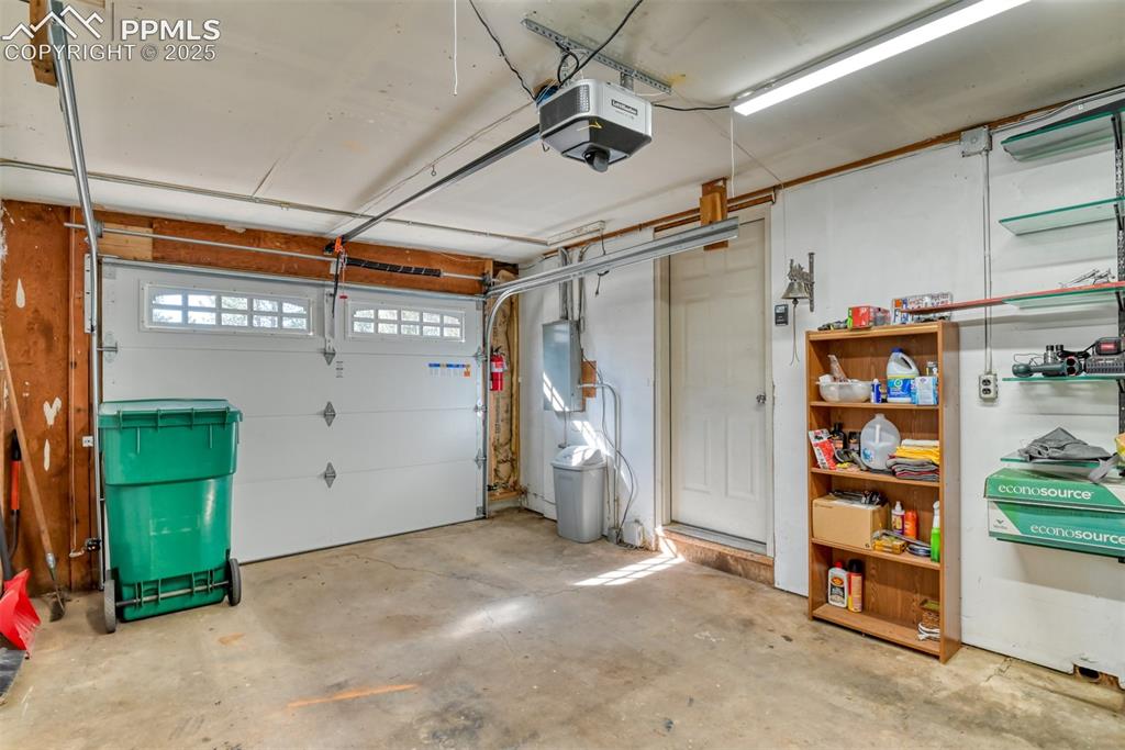Image 23 of 43: Garage with a garage door opener and electric panel