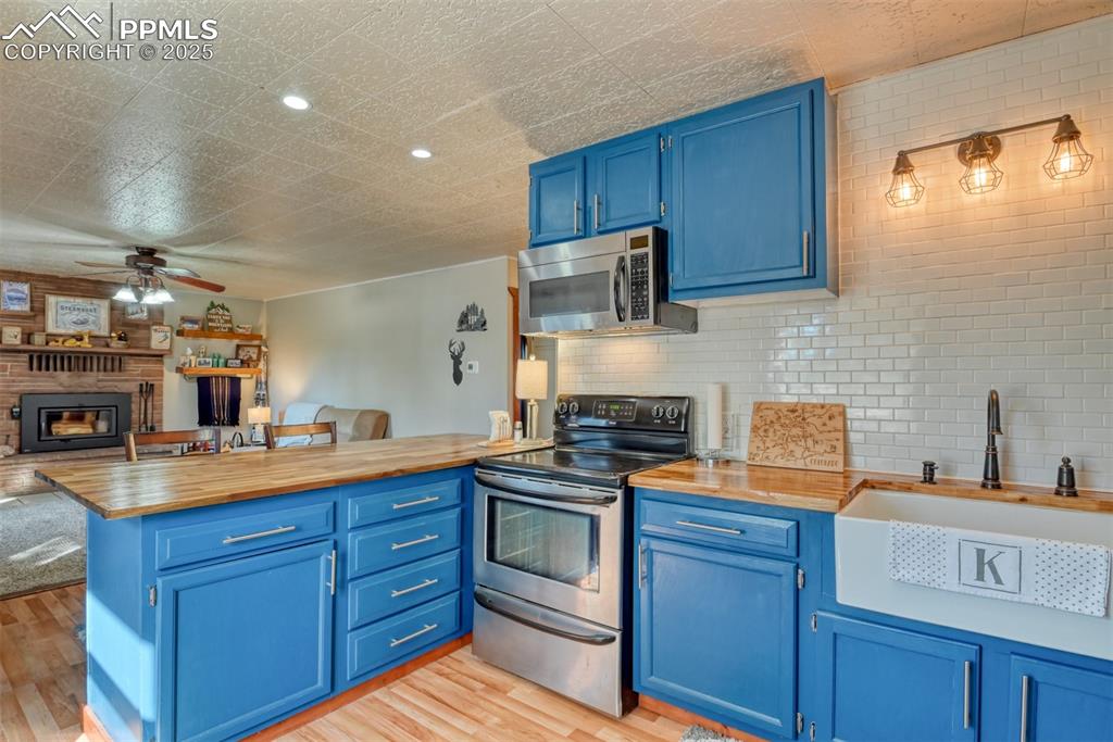 Image 27 of 42: Kitchen featuring blue cabinetry, open floor plan, appliances with stainles