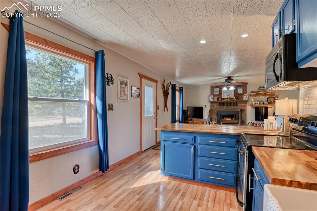 Image 27 of 43: Kitchen featuring blue cabinetry, stainless steel electric range oven, wood