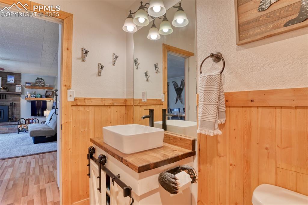 Image 29 of 43: Bathroom featuring wood walls, wood finished floors, vanity, a chandelier,