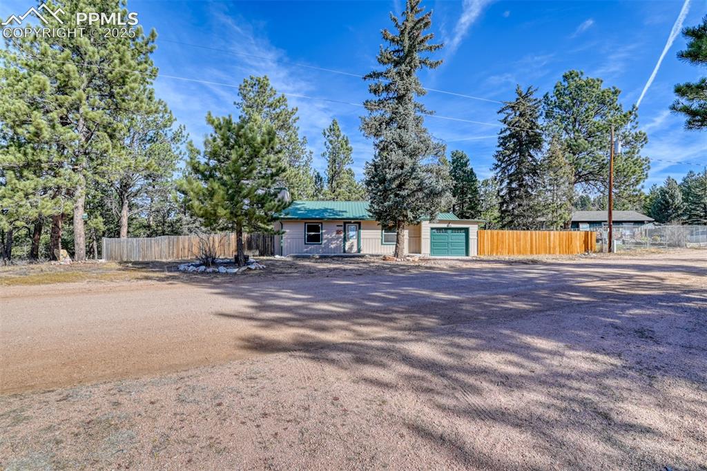 Image 3 of 43: Ranch-style home with a garage, a metal roof, and driveway