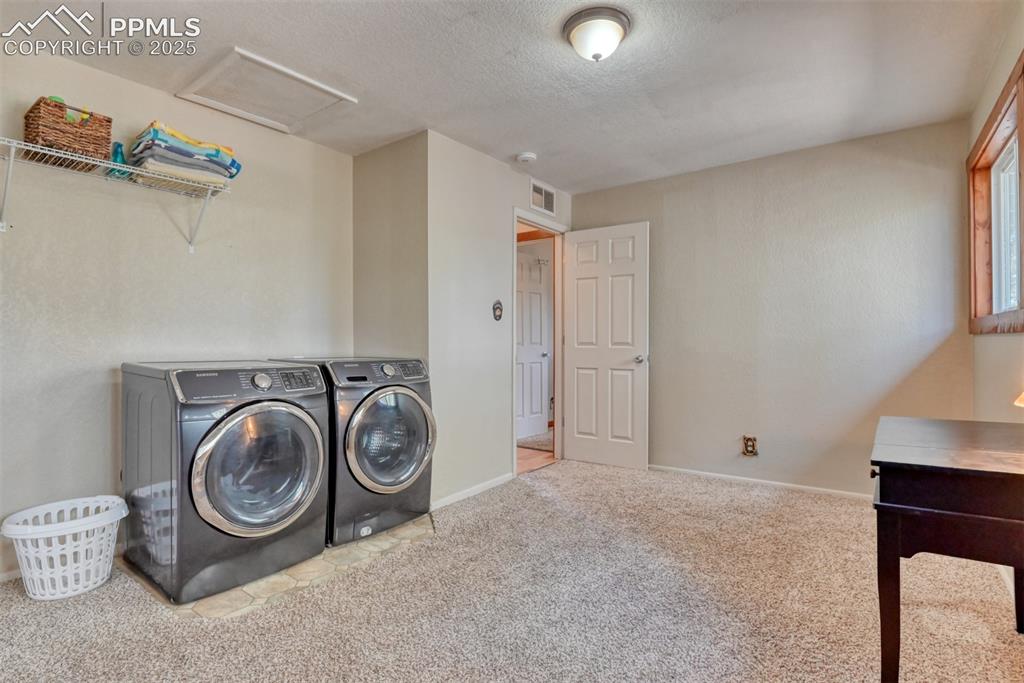 Image 36 of 43: Laundry area with washer and dryer, carpet flooring, a textured ceiling, an