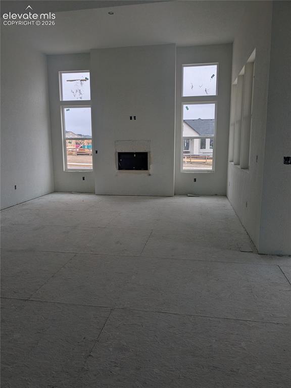 Image 12 of 45: Living area featuring a floor-to-ceiling fireplace, double-stacked windows,