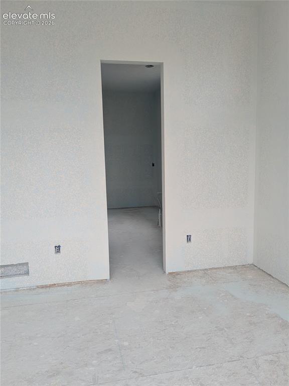 Image 15 of 45: Interior space featuring textured walls, a doorway opening to an additional