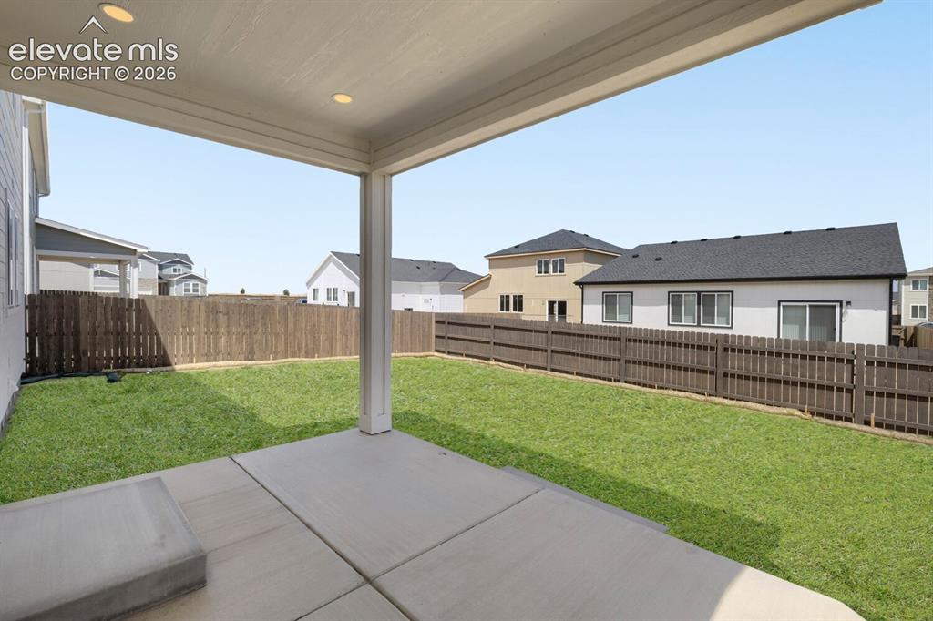 Image 27 of 31: Fully landscaped back yard with covered patio