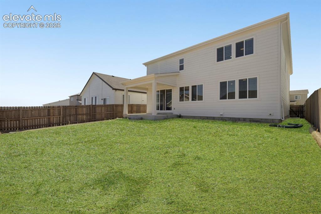 Image 28 of 31: Fully landscaped back yard with covered patio