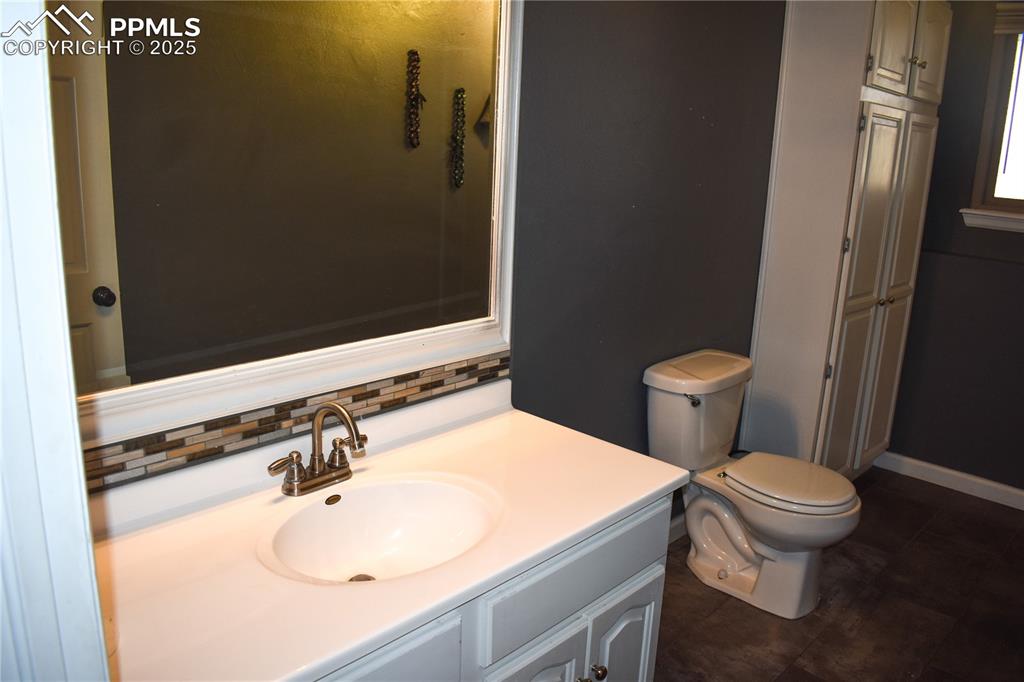 Image 13 of 24: Bathroom with toilet, vanity, baseboards, and decorative backsplash