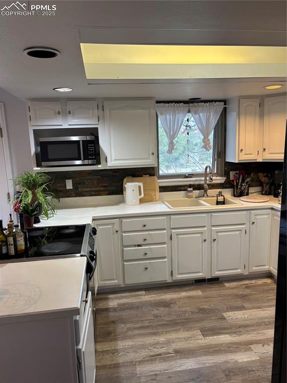 Image 22 of 24: Kitchen featuring white cabinets, light countertops, wood finished floors,