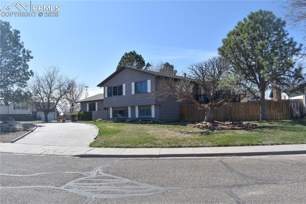 Image 3 of 24: View of front of property featuring concrete driveway, fence, and a front l