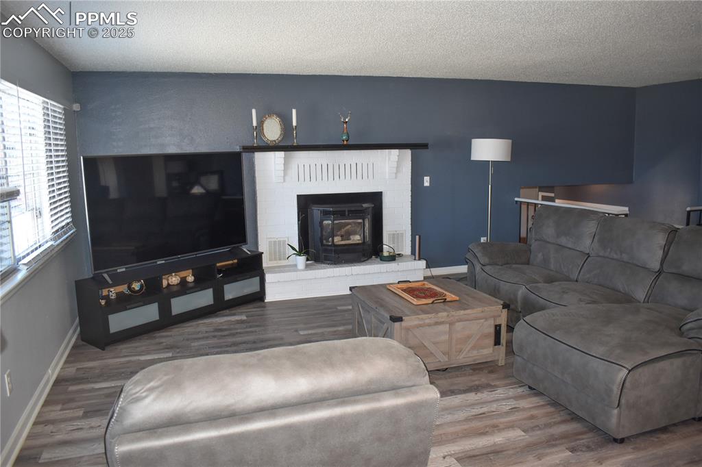 Image 5 of 24: Living area with baseboards, visible vents, wood finished floors, and a tex