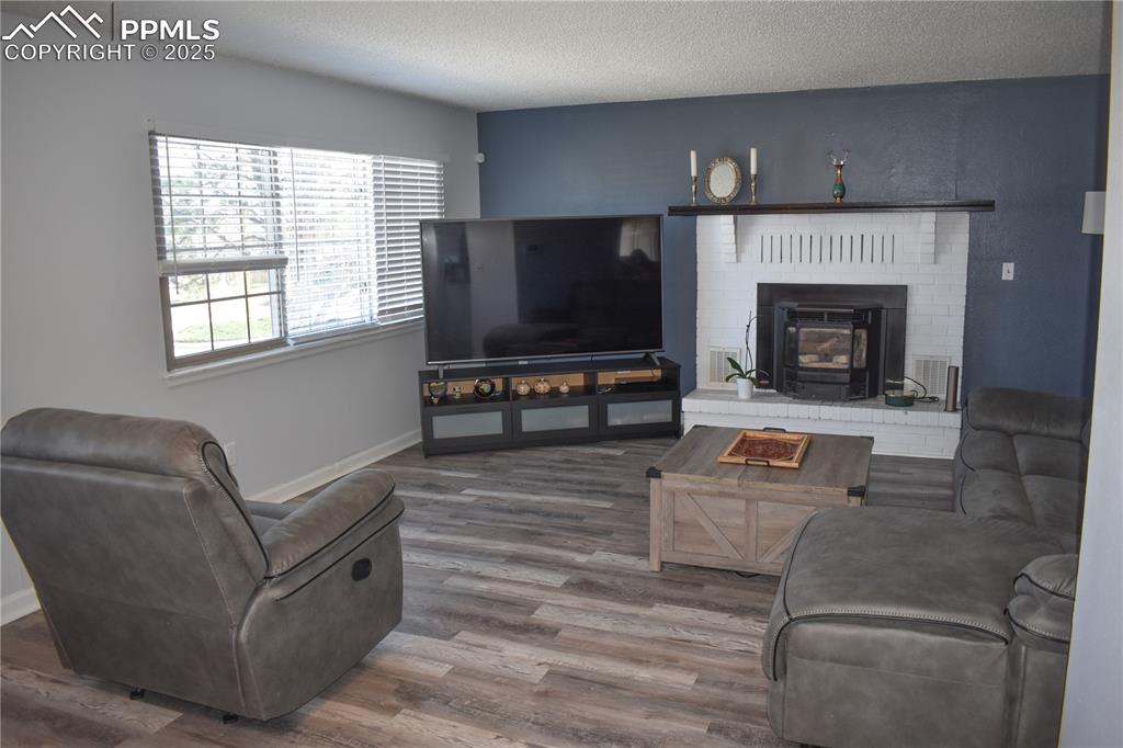 Image 6 of 24: Living area featuring a textured ceiling, baseboards, and wood finished flo