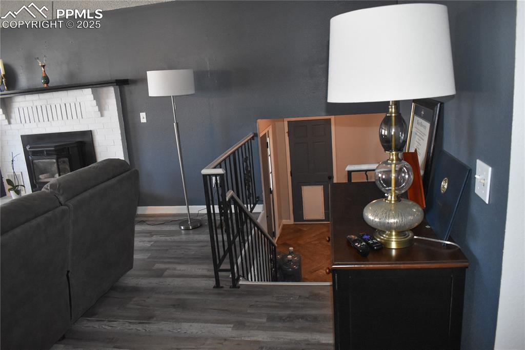 Image 8 of 24: Stairway with baseboards, wood finished floors, and a brick fireplace