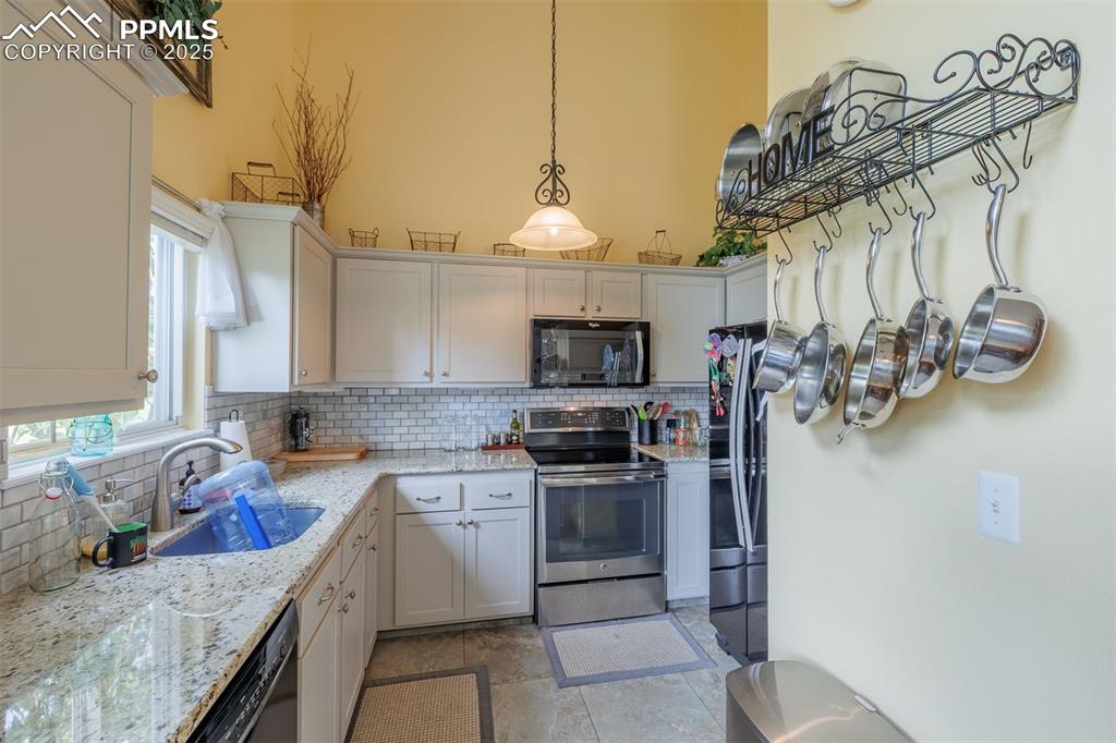 Image 5 of 15: Kitchen featuring black appliances, decorative backsplash, hanging light fi