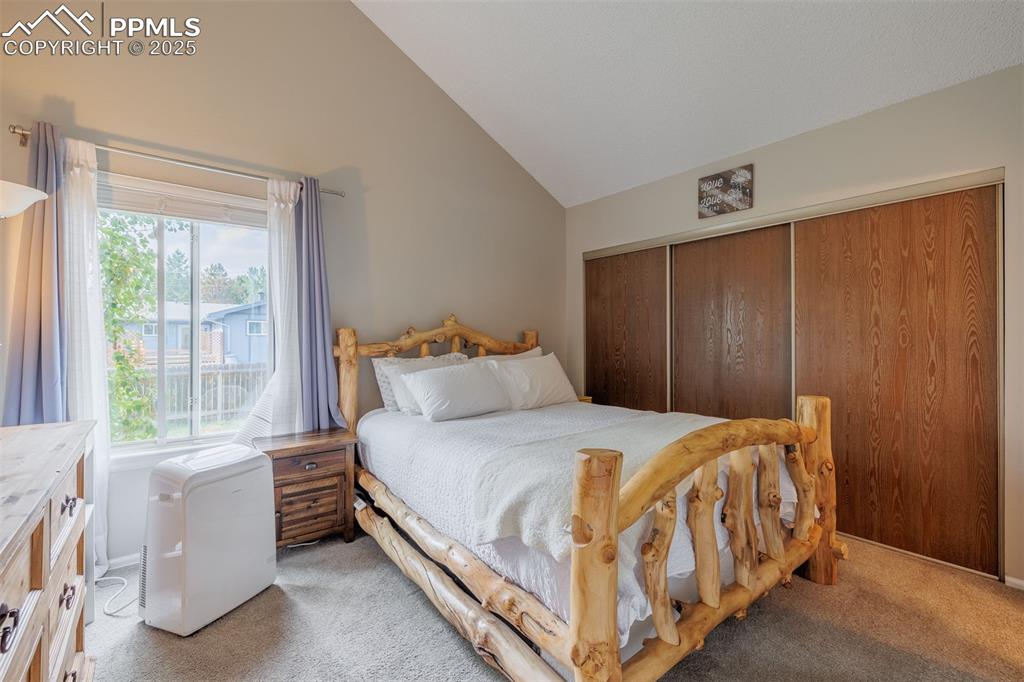 Image 7 of 15: Bedroom featuring vaulted ceiling, light carpet, and a closet